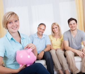 two girls and two boys are sitting on a couch holding a piggy box