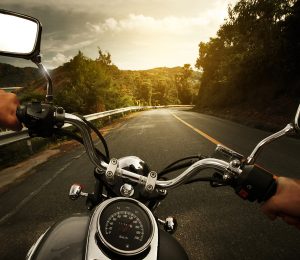 man riding a motorcycle with a great view and empty road.